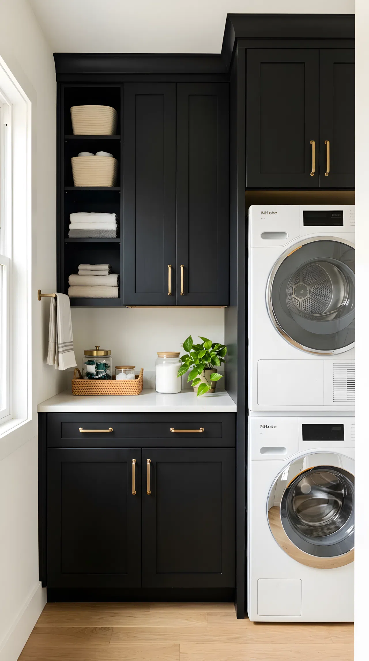 Real-life stock photo style, black shaker cabinets with unlacquered brass pulls in a narrow laundry closet, neatly made, beautifully arranged, organized, clean, bright natural light, vibrant colors, no people, no text overlay, paint color RGB(20,20,20)