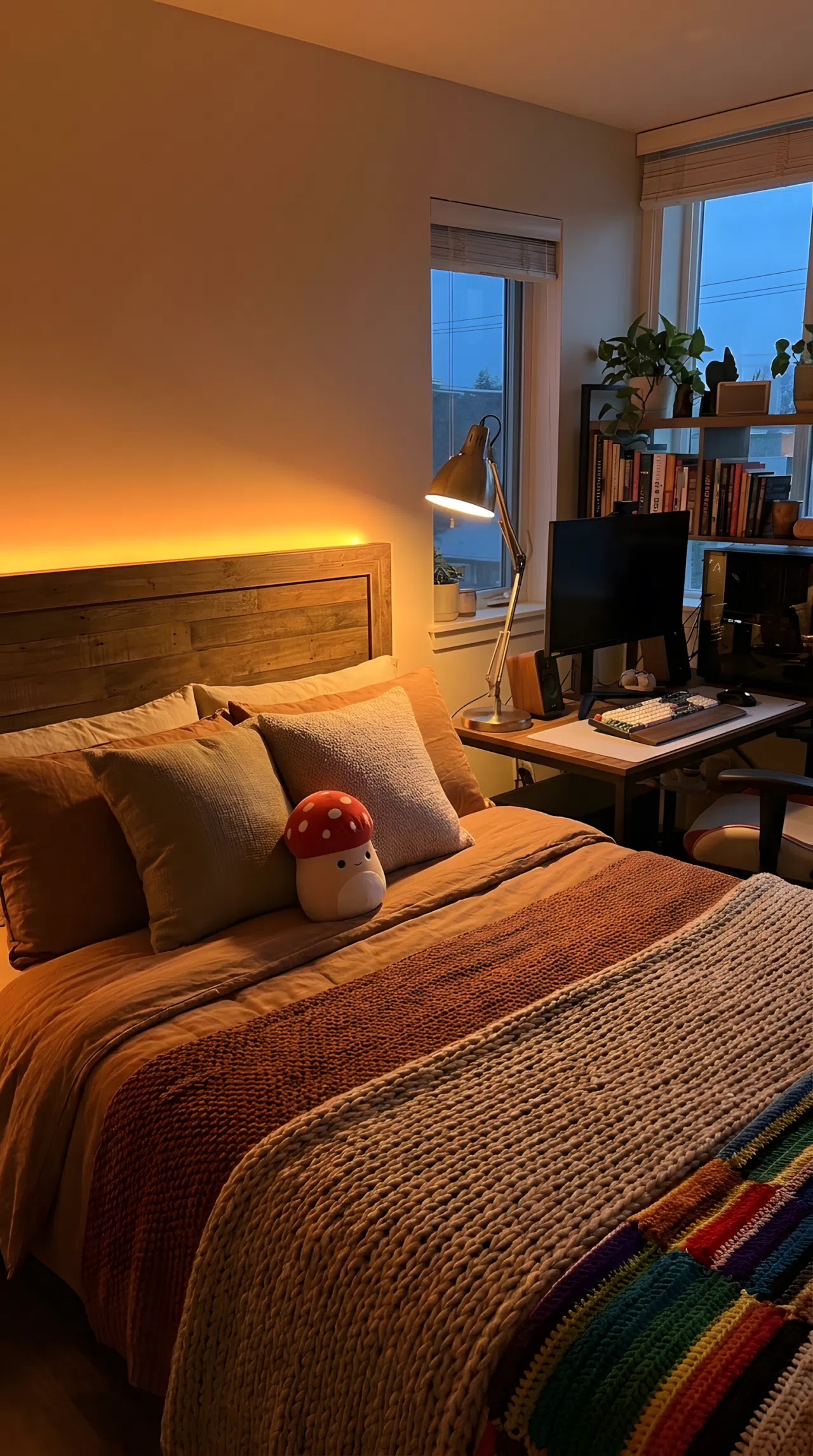 A cozy neatly made bedroom corner at dusk with a soft ambient light positioned low behind the headboard casting warm glow across a beautifully arranged bed, small red mushroom-shaped plush toy on the pillow, angled desk lamp placed beside a gaming setup avoiding overhead glare, organized and clean, warm inviting light, real-life lifestyle photography, vibrant colors, no people, no text overlays.