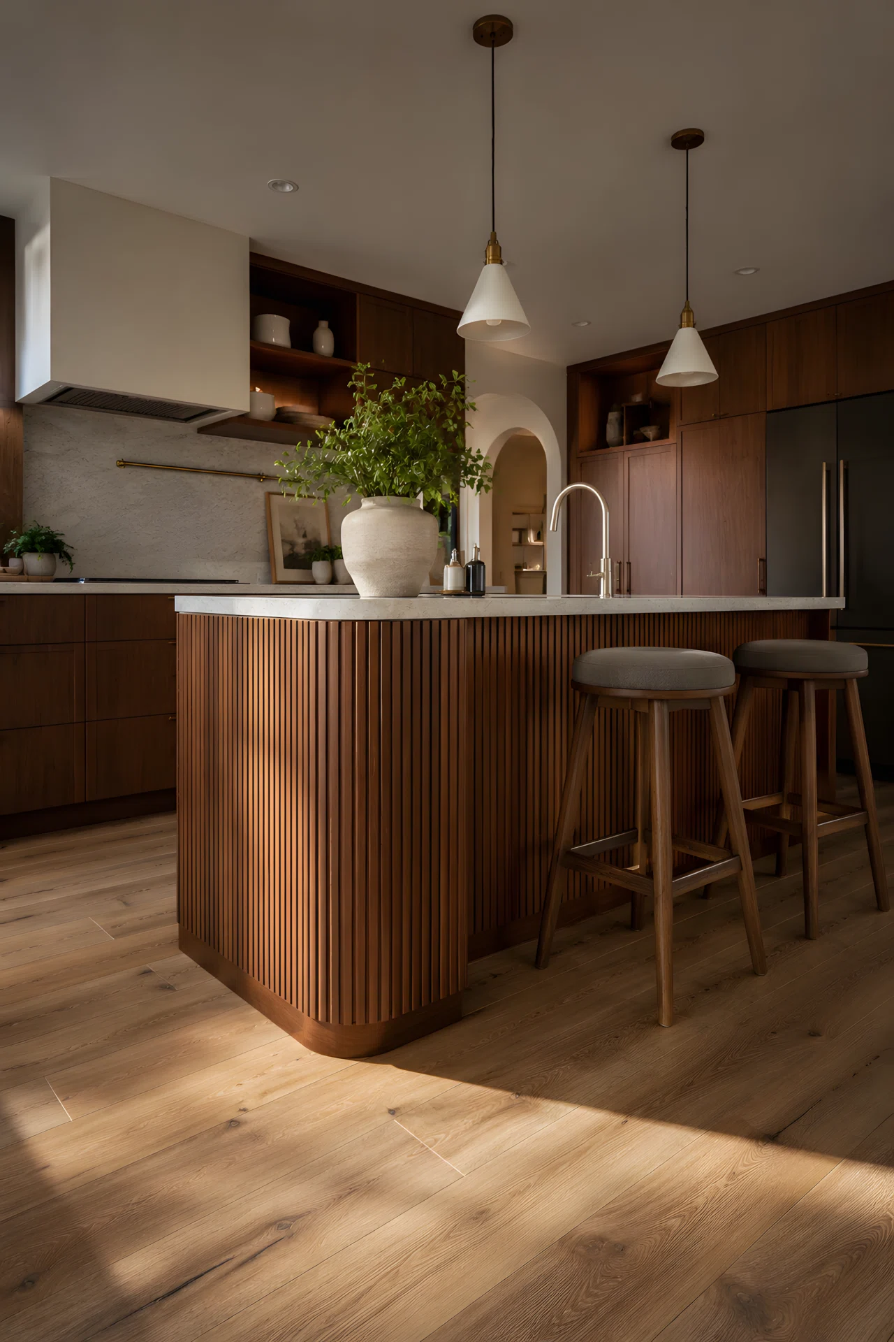 Wide-angle stock photograph of a kitchen island with fluted wood cabinet panels in warm walnut tone, soft directional light emphasizing the grooves and texture, full room visible from a dramatic low wide angle, vibrant natural tones, photographic realism, no illustration.