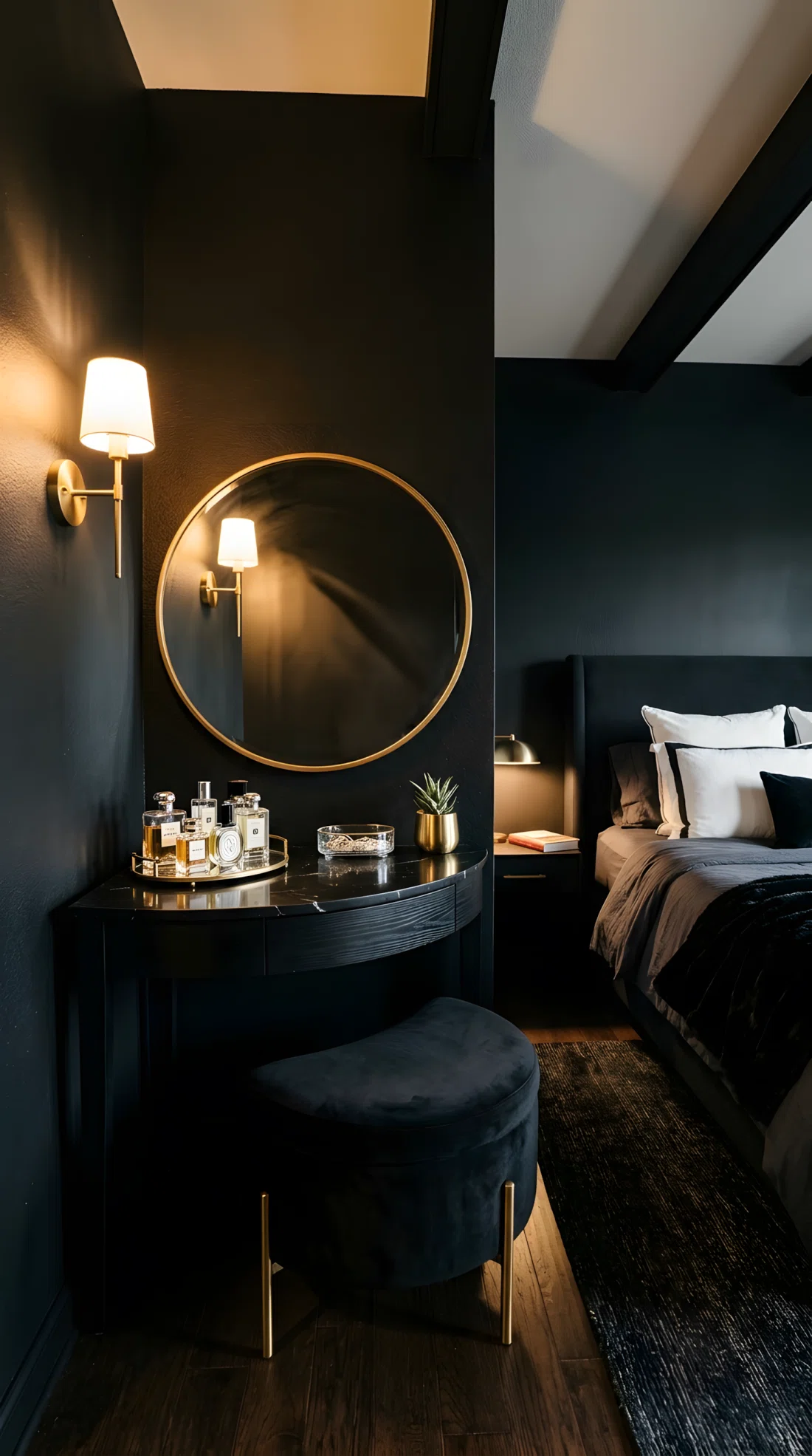 Wide-angle real photo of a black bedroom corner with a curved vanity table, round mirror in slim gold frame, curved black velvet stool, small tray with perfume bottles neatly arranged, side-positioned warm light source casting soft shadows across the mirror instead of overhead lighting, black walls, dramatic wide camera angle capturing the full corner and part of the bed, photographic stock photo style, vibrant tones